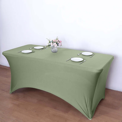 Green fitted table cover with plates and a vase of flowers.
