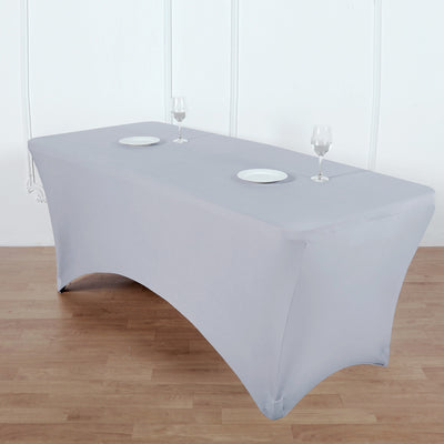 Gray fitted table cover with plates and glasses on a wooden floor.