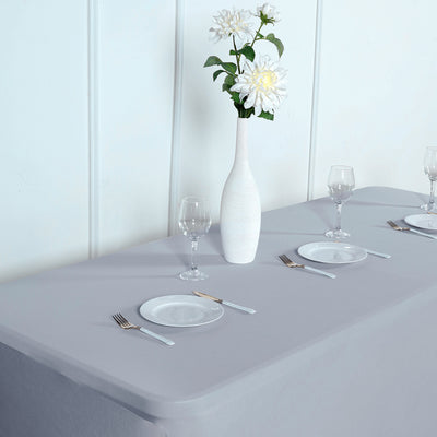 Table setting with gray tablecloth, white vase, and plates on a clean surface.