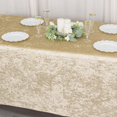 Elegant gold tablecloth with white plates and floral centerpiece for dining setup.