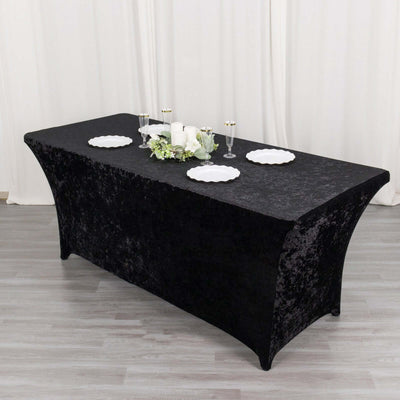 Black tablecloth draped over a rectangular table with decorative plates and candles.