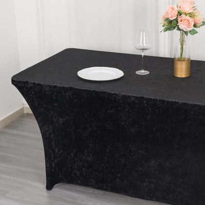 Black tablecloth draped over a table with a plate and vase of flowers.