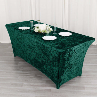 Green velvet tablecloth draped over a table with decorative items and plates.