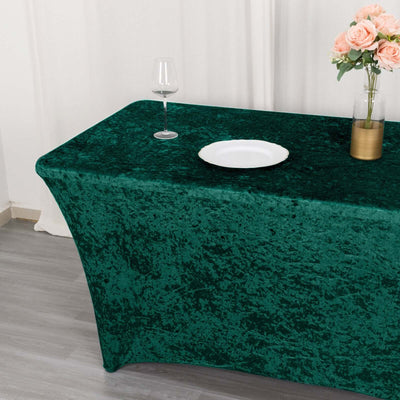 Green velvet tablecloth on a decorated table with glass and flowers.