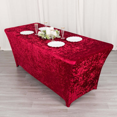 Red velvet table cover draped over a banquet table with dishes and decor.