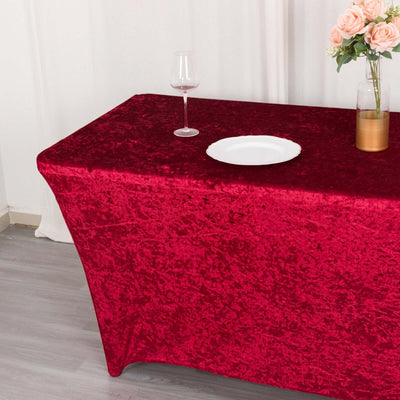 Red velvet tablecloth on a dining table with a plate and wine glass.