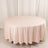 Round pink tablecloth on a round table against a plain backdrop