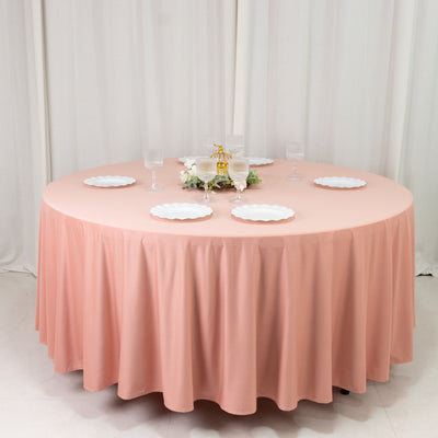 Round pink tablecloth draped over a circular table set for a meal.