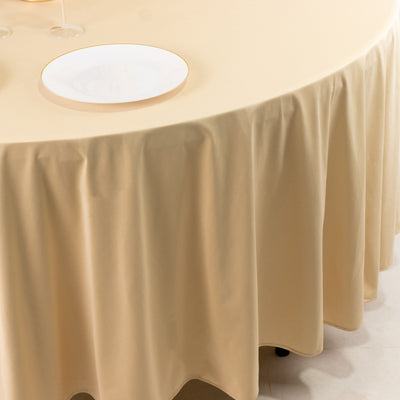 Beige tablecloth draped over a round table with a white plate on top.