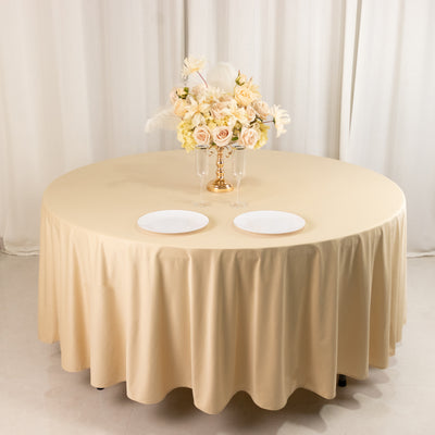 Round beige tablecloth with floral centerpiece and two white plates.