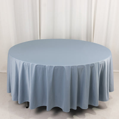 Round blue tablecloth on a circular table against a plain backdrop.