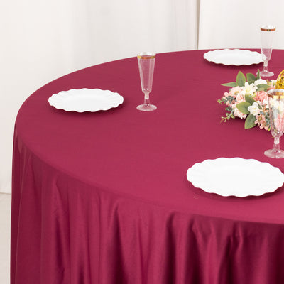 Burgundy tablecloth with white plates and floral centerpiece