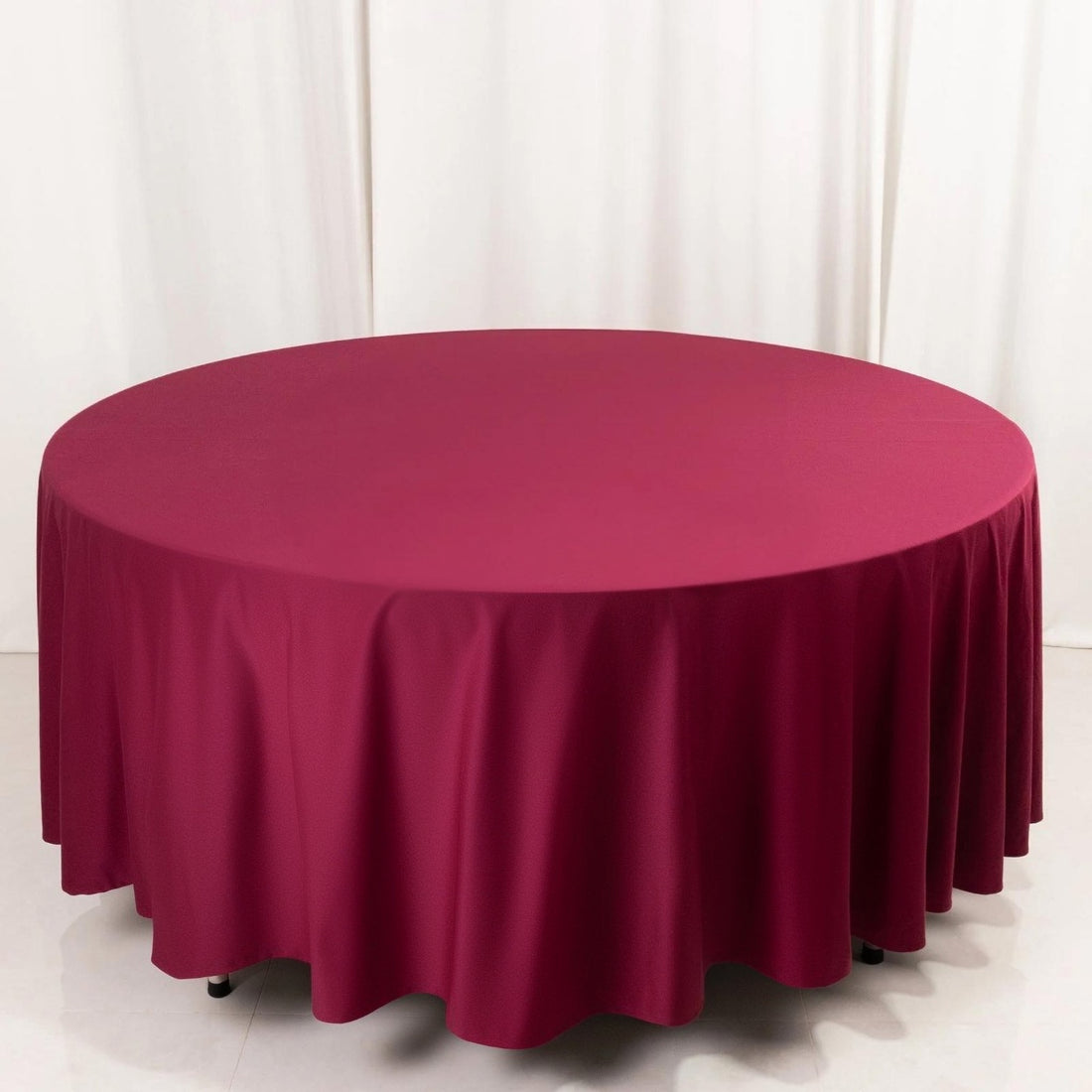 Round burgundy tablecloth on a plain backdrop