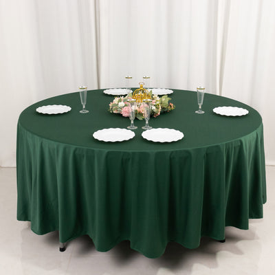 Green tablecloth on a round table set with plates and decorative centerpiece.