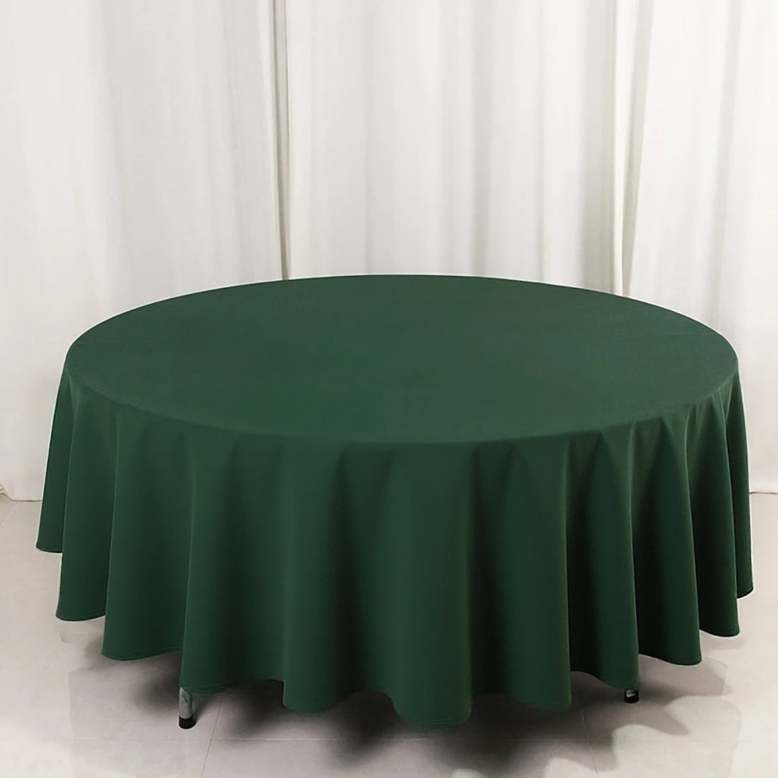 Green round tablecloth on a table against a plain backdrop