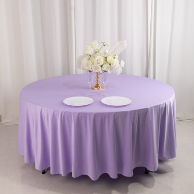 Round lavender tablecloth with white plates and floral centerpiece.