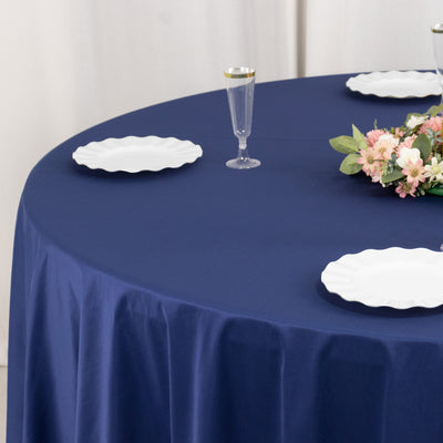 Navy tablecloth with white plates and floral centerpiece on a dining table.
