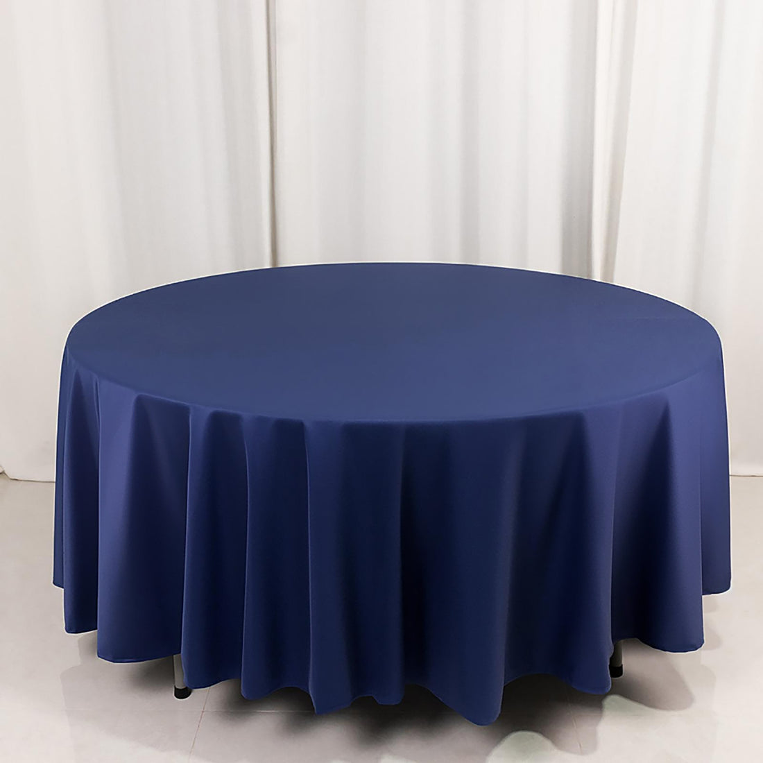 Round navy tablecloth with draped edges on a plain backdrop.
