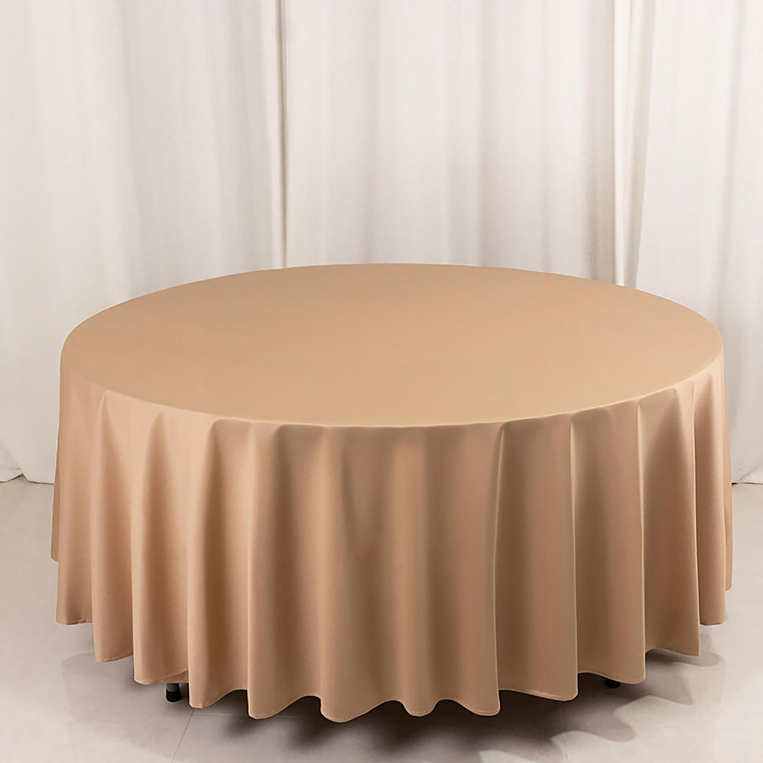 Round beige tablecloth on a circular table, smooth fabric draping elegantly.