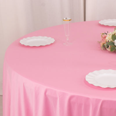 Pink tablecloth with white plates and floral arrangement on a styled table setting.