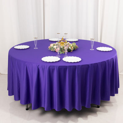 Round purple tablecloth draped over a circular table with decorative plates and centerpiece.