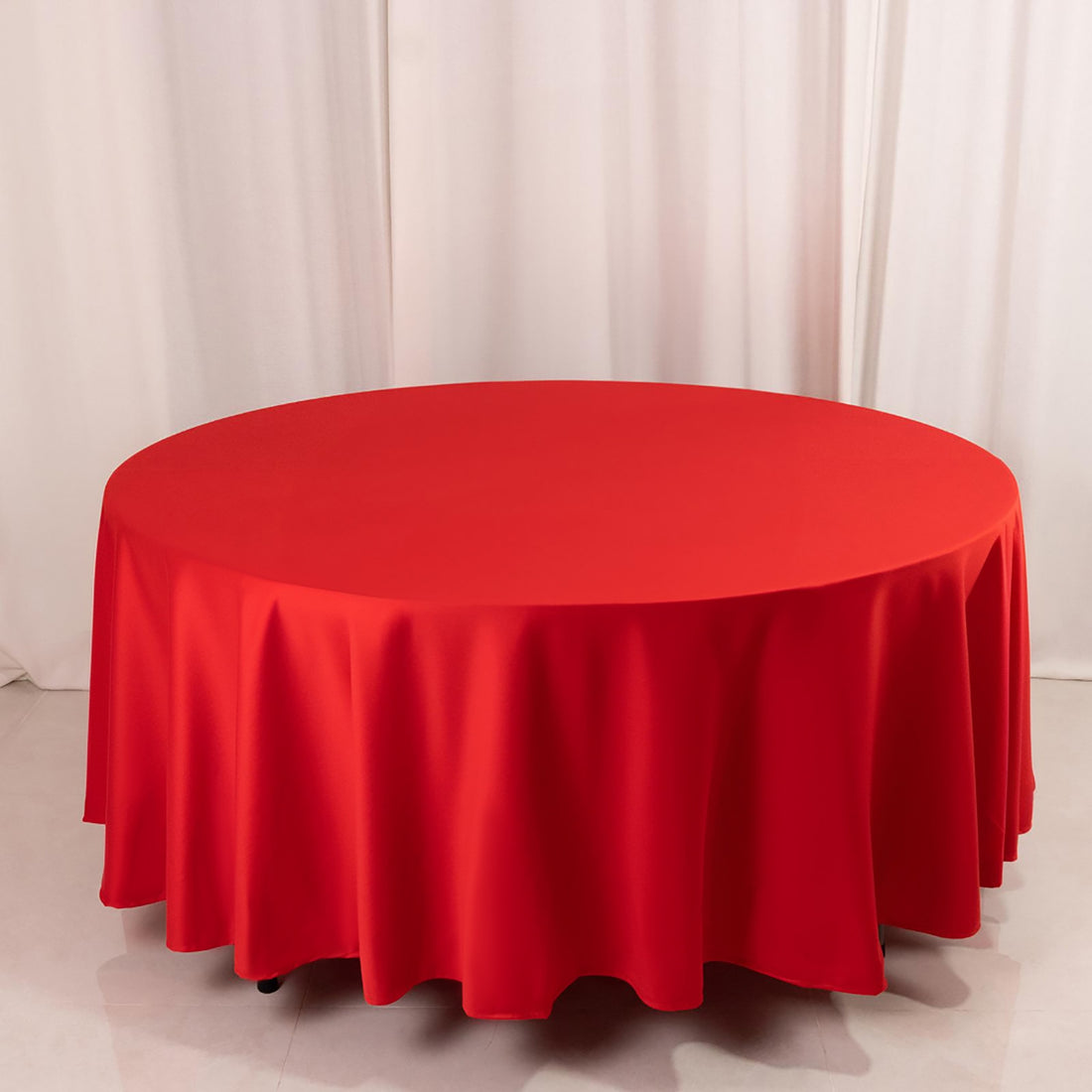 Red round tablecloth with elegant drape on a plain background.