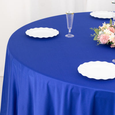 Blue tablecloth with white plates and floral centerpiece on a round table.