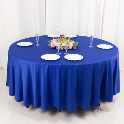 Round blue tablecloth draped over a table with decorative plates and centerpieces.