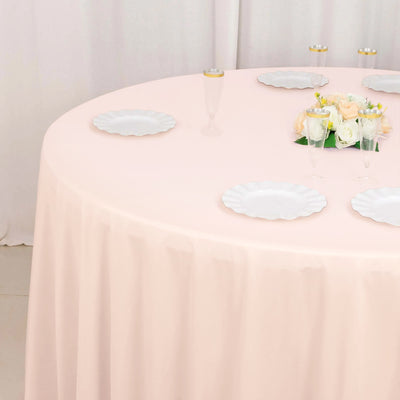 Pink tablecloth draped over a round table with white plates and floral centerpiece.