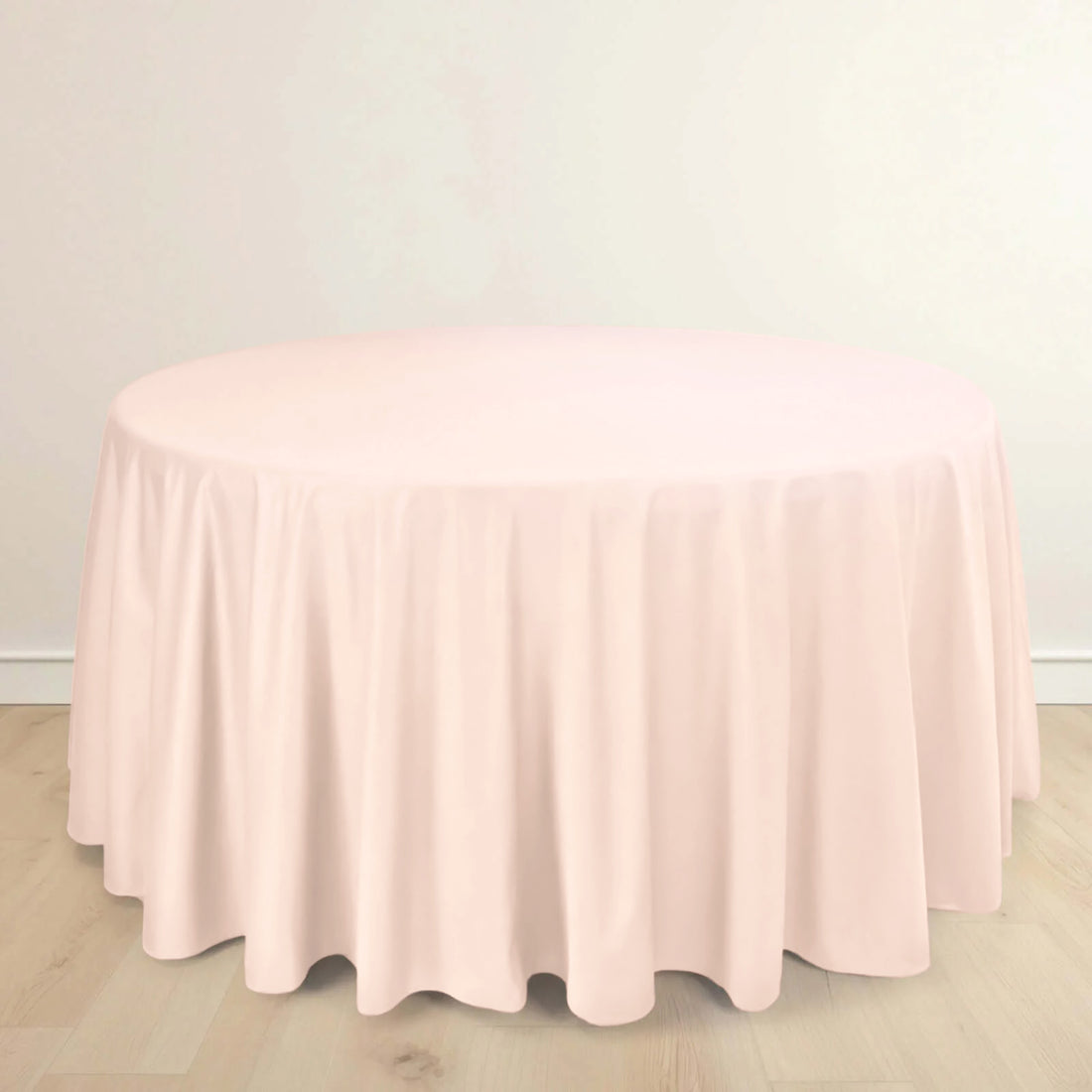 Round pink tablecloth on a wooden floor.