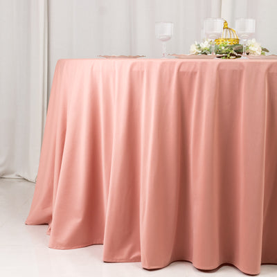 Pink satin tablecloth draped over a dining table with elegant glassware.