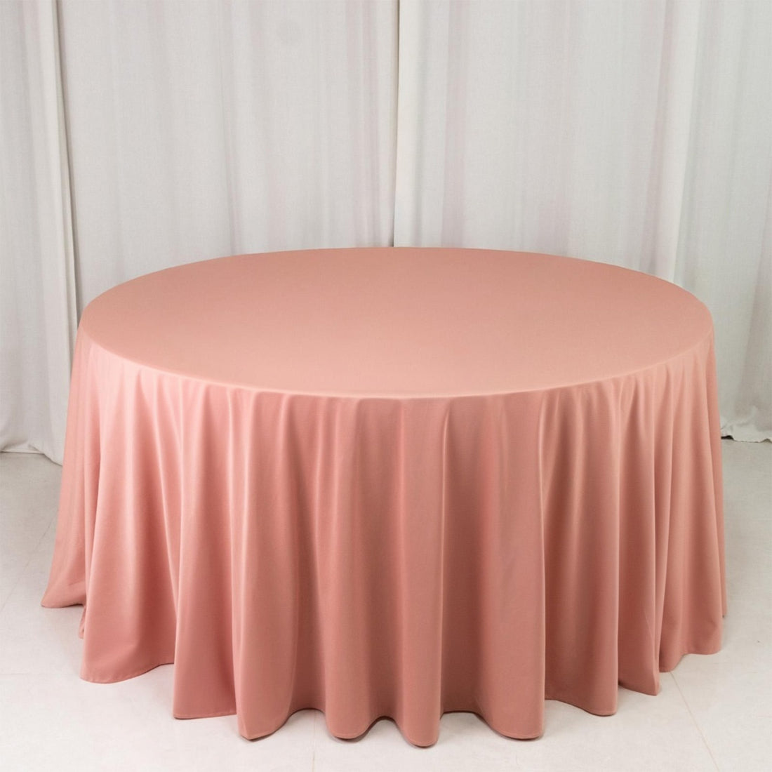 Round blush pink tablecloth on table in studio setting