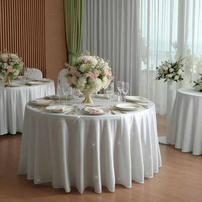Elegant tables set for a wedding with floral centerpieces and sparkling tablecloths.