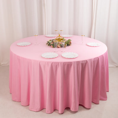 Round pink tablecloth with white plates and decorative centerpiece.