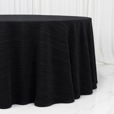 Black pleated round tablecloth on a table against a white backdrop