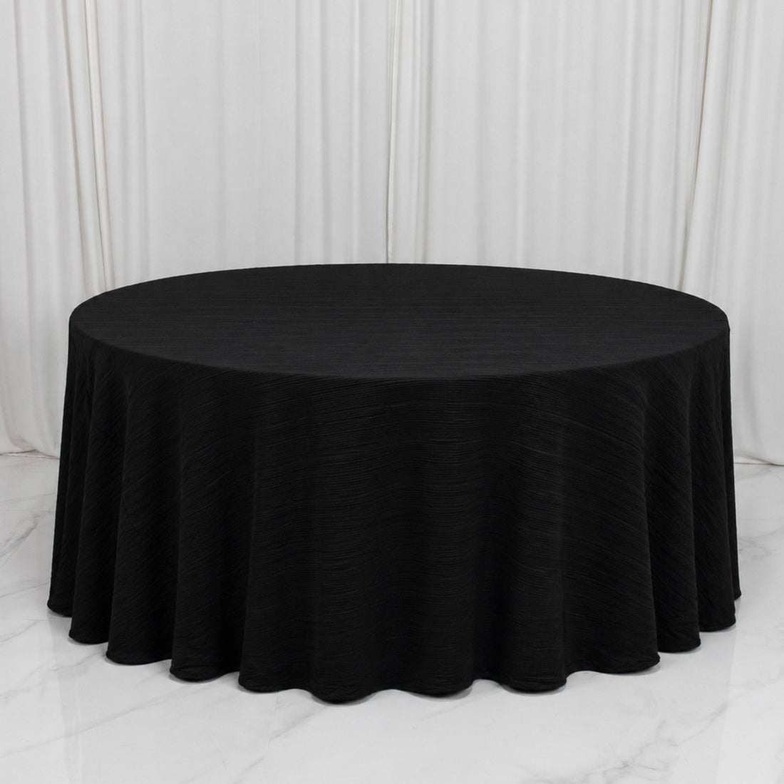 Black round banquet table with elegant draped tablecloth on white backdrop