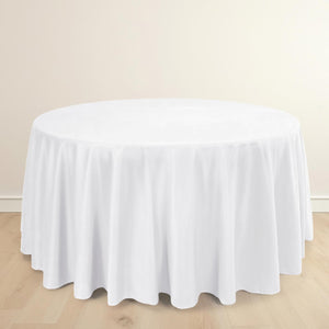 Round white tablecloth with elegant draping on a wooden surface.