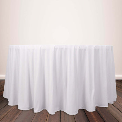 White tablecloth draped over a round table on wooden floor