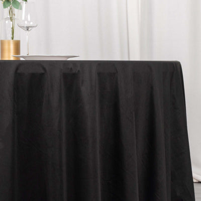 Black tablecloth draped elegantly on a table with a glass and vase in the background.