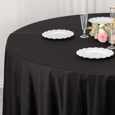 Elegant black tablecloth with white plates and floral arrangement.