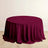 Burgundy round tablecloth draped over a table on a light wooden floor.