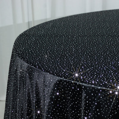 Black tablecloth with sparkling star pattern on a plain backdrop.