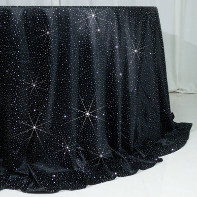 Black tablecloth with sparkling rhinestones on a plain backdrop.