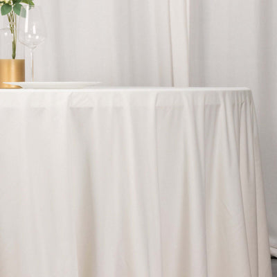 White tablecloth draped over a table with a glass and plant centerpiece.