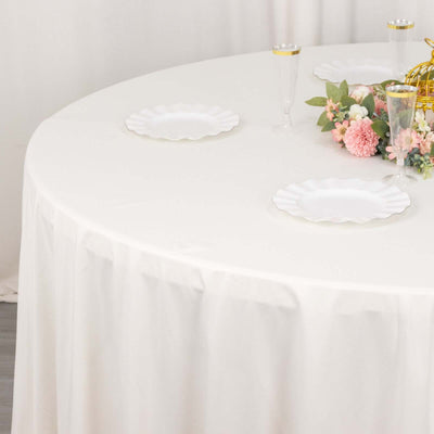 Round table set with white plates and floral arrangement.