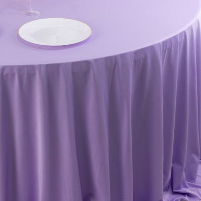 Purple tablecloth draped elegantly over a round table with a white plate on top.