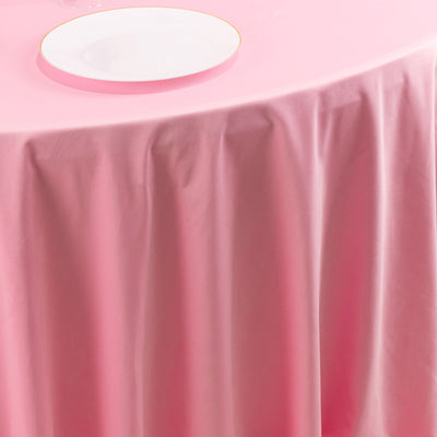 Pink tablecloth draped elegantly over a table with a white plate on top.