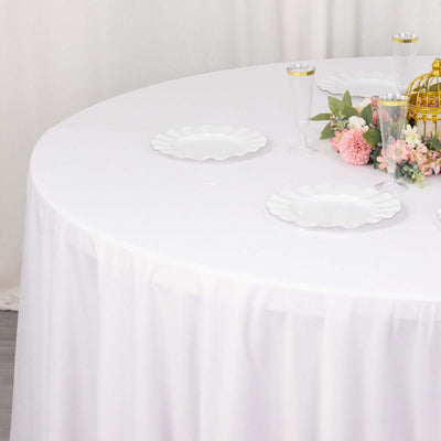 Elegant round table set with white plates and floral decor.