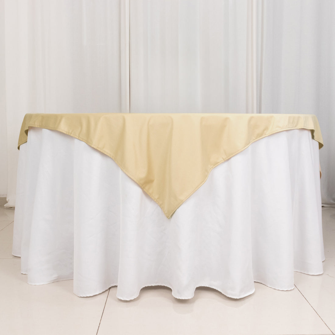Gold table cover draping over a white tablecloth in a studio setting.