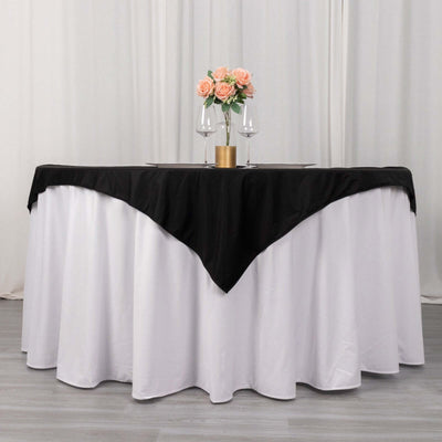 Elegant round table set with black and white linens, adorned with flowers and glasses.